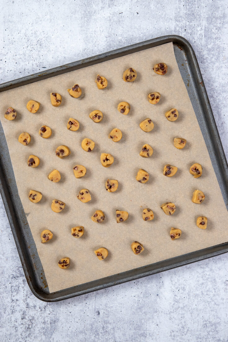 Tiny cookie dough balls on a baking sheet.