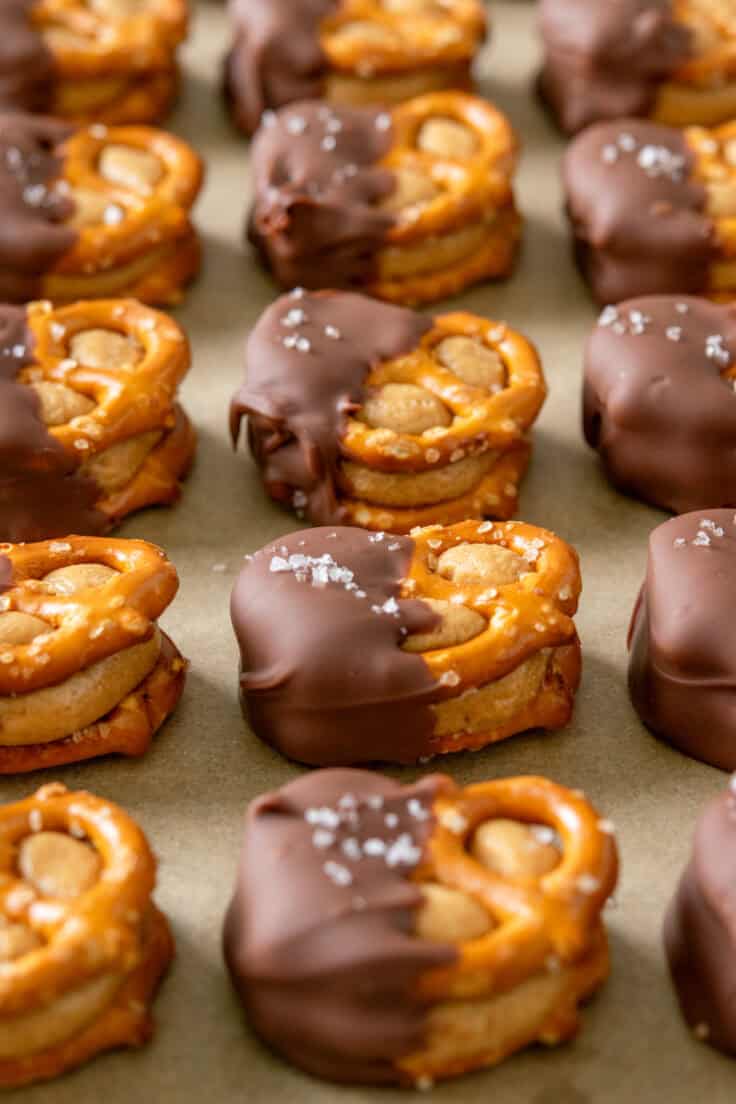 Close-up view of homemade pretzel bites on a tray showing the thick peanut butter center and how the chocolate has hardened after cooling.