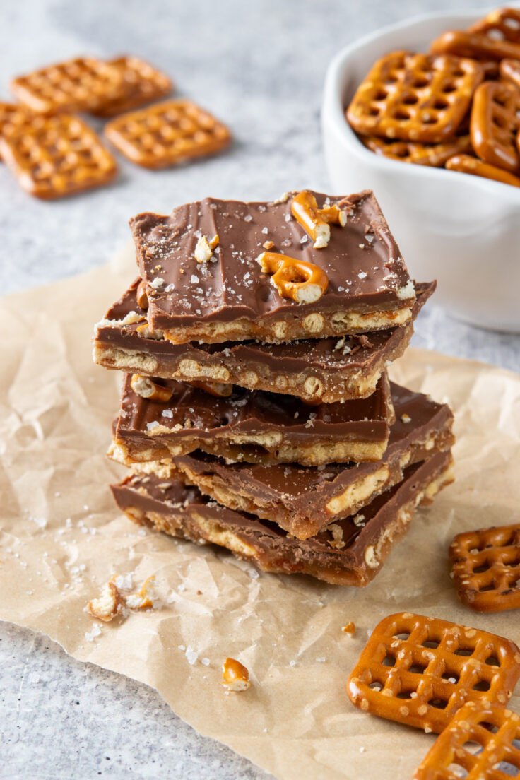 A close-up view of a stack of pretzel bark showing layers of pretzels, toffee and chocolate. The bark is sprinkled with sea salt.