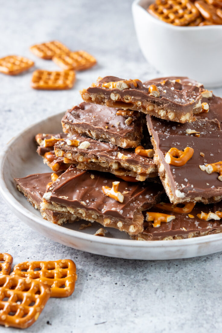 A plate piled high with pieces of homemade salted caramel pretzel bark.