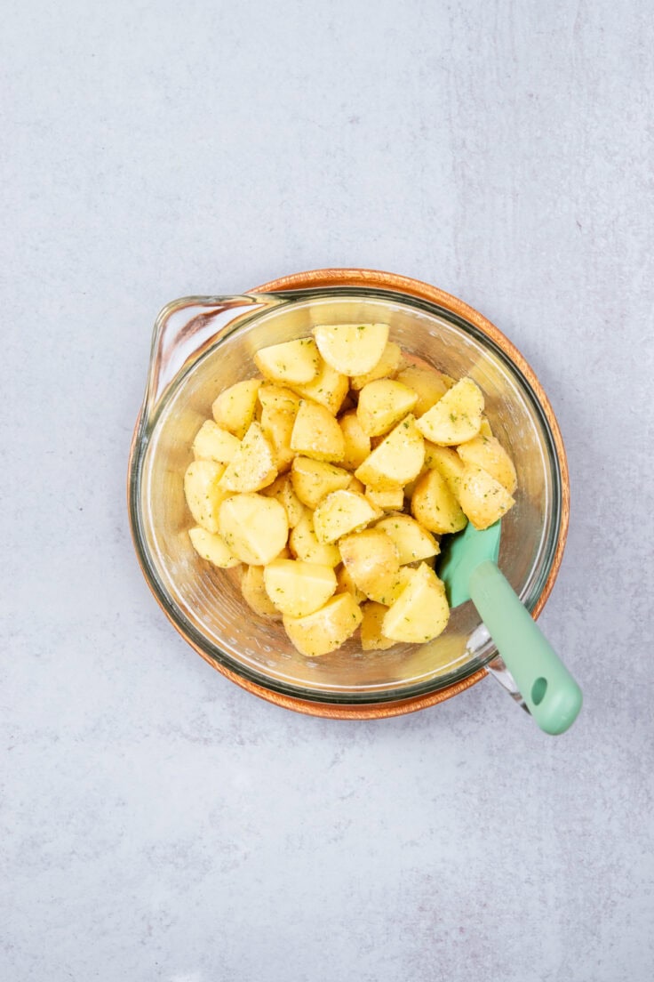 Yellow new potatoes in a bowl coated in oil and ranch seasoning mix.