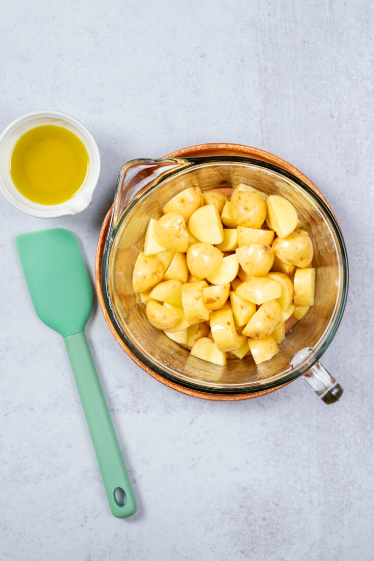 A bowl of chopped potatoes in a bowl. The potatoes have been coated in oil.