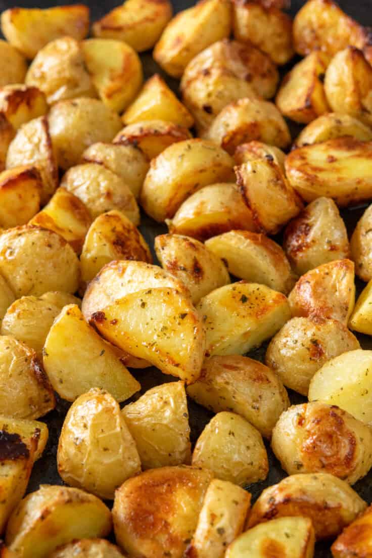 A baking sheet covered in golden-brown roasted potatoes. can see the crispy edges and caramelized sides, as well as seasoning.