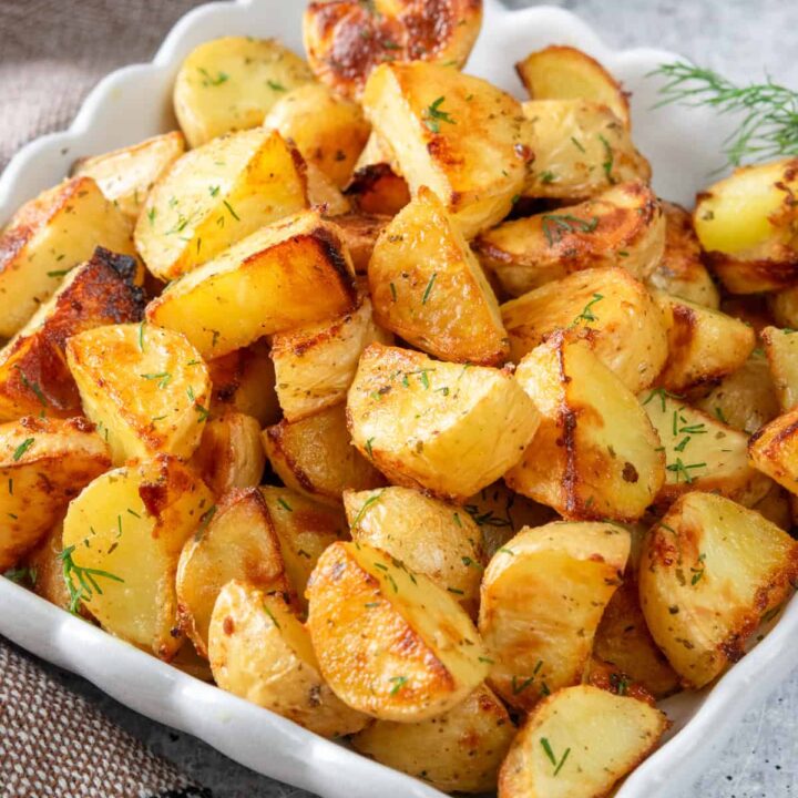 Crispy ranch roasted potatoes in a serving dish, garnished with fresh dill.