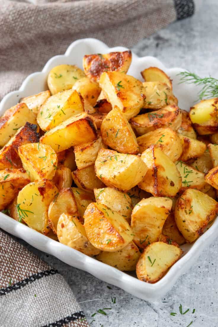 Crispy ranch roasted potatoes in a serving dish, garnished with fresh dill.