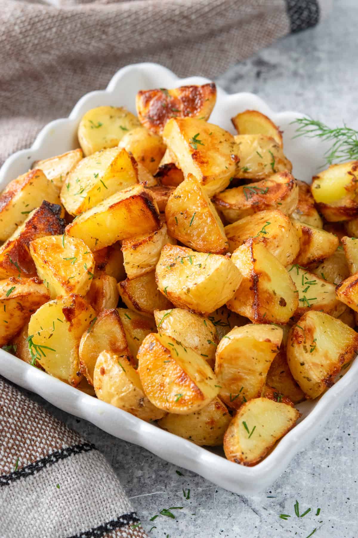 Crispy ranch roasted potatoes in a serving dish, garnished with fresh dill.