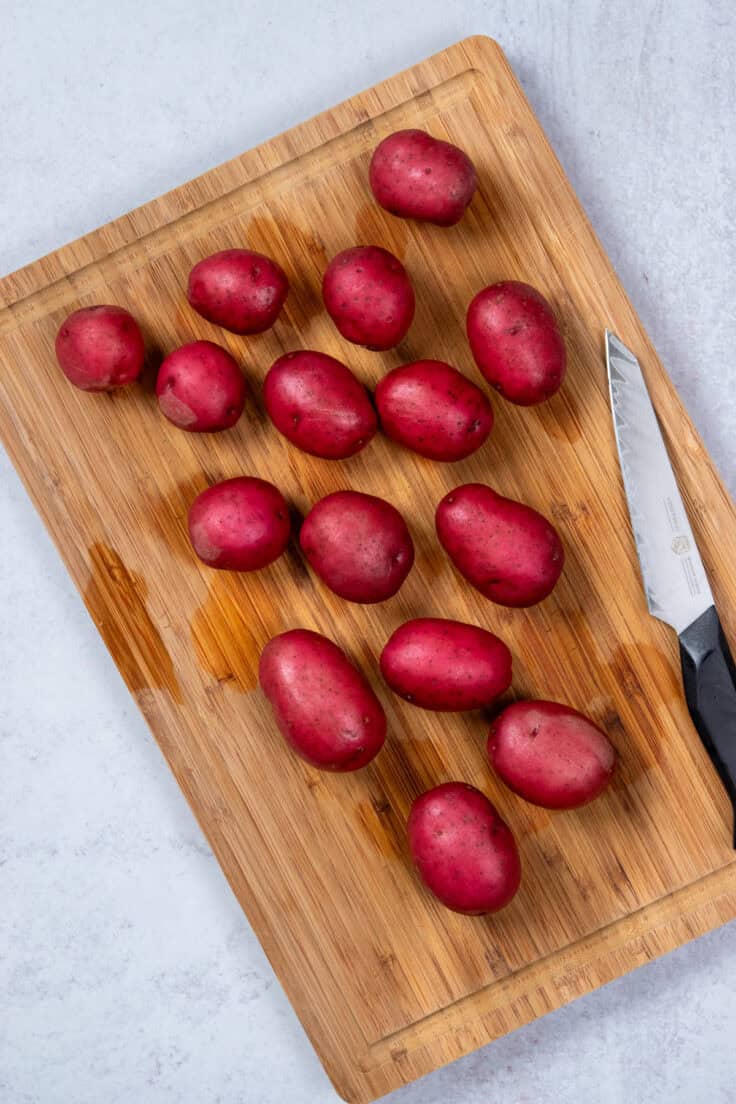 Baby red potatoes on a cutting board with knife.