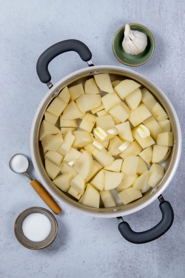 Potatoes and garlic in a large pot filled with water being boiled for mashed potatoes.