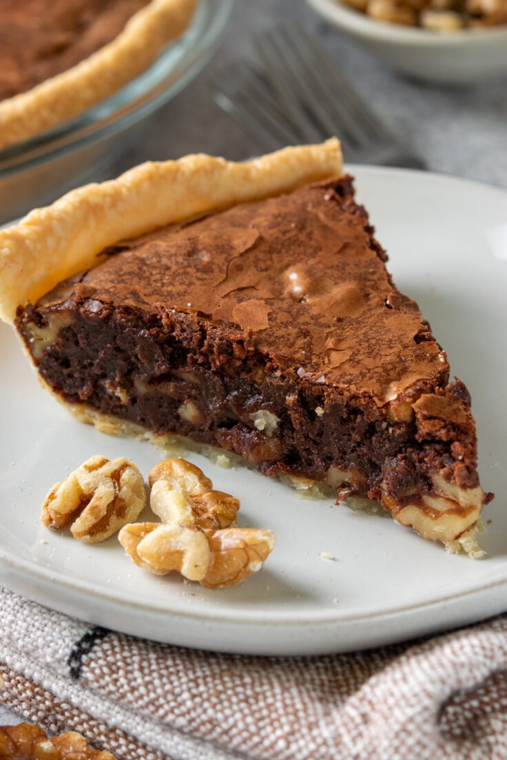 A slice of fudge pie that looks like a homemade brownie in pie crust. The top has a glossy, crackly skin just like brownies, and the inside is rich and gooey.