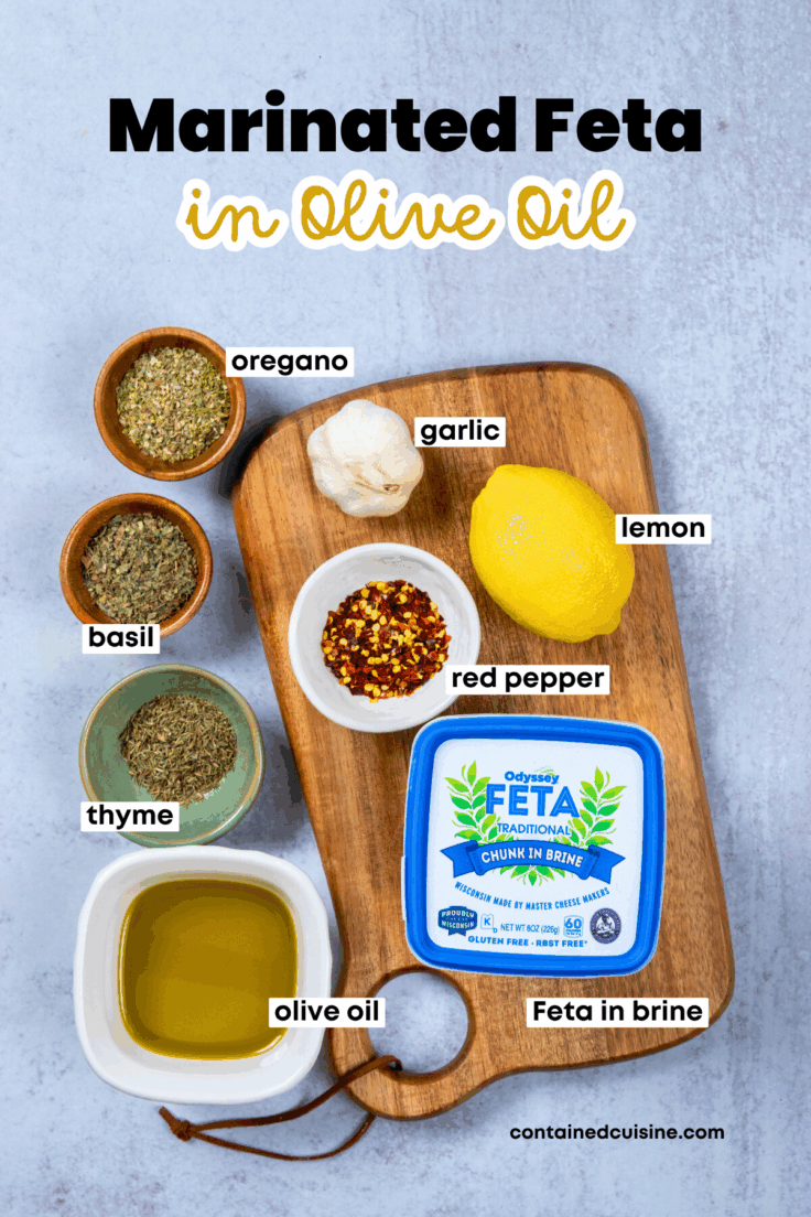 All the ingredients needed to make marinated feta, including dried oregano, basil and thyme, garlic, red pepper flakes, lemon zest, feta in brine, and extra virgin olive oil.