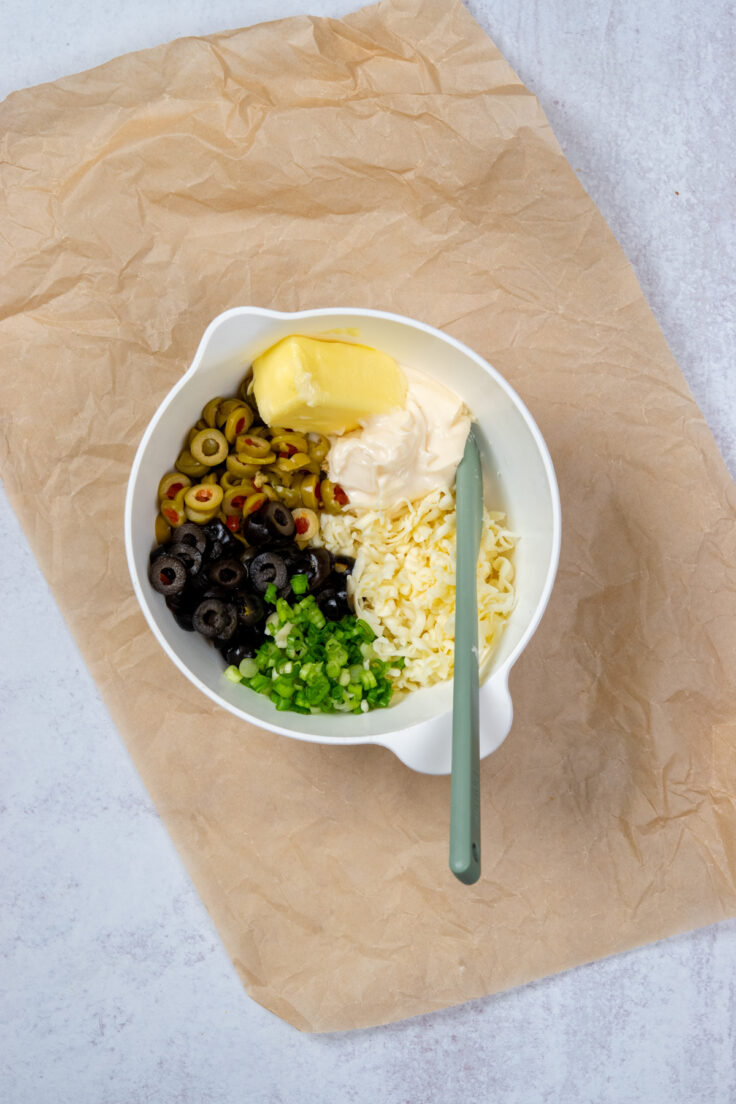 A mixing bowl with all the ingredients needed for the olive cheese spread.