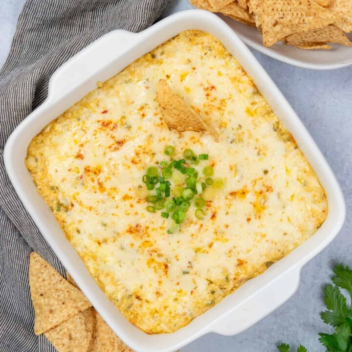 Hot, cheesy chicken enchilada dip in a baked dish with tortilla chips on the side, ready for serving.