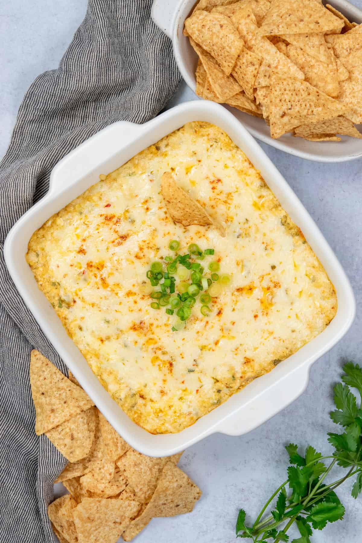Hot, cheesy chicken enchilada dip in a baked dish with tortilla chips on the side, ready for serving.