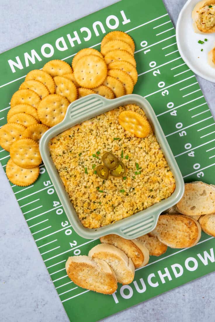 Jalapeño popper dip served on a football field tray with a variety of crackers, ideal for game day or Super Bowl parties.