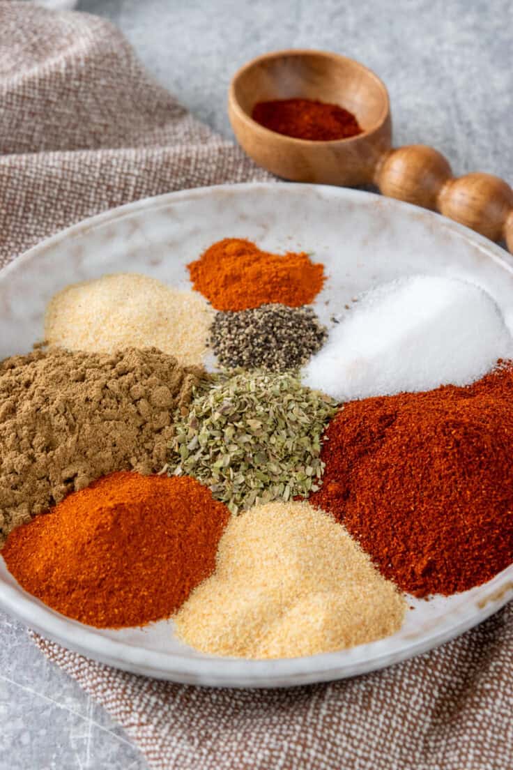 Close-up of individual fajita seasoning spices piled next to each other on a plate.