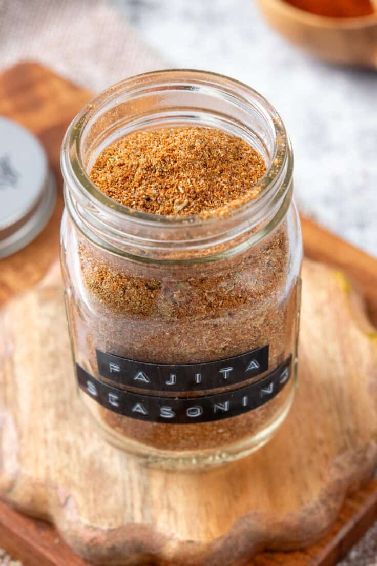 Top-down view of a glass jar filled with colorful homemade fajita seasoning.