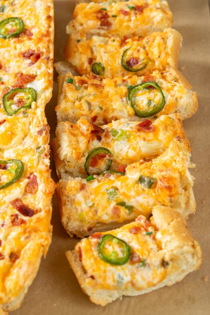 Sliced jalapeño popper cheese bread loaded with melted cheese, crispy bacon, and fresh jalapeños.