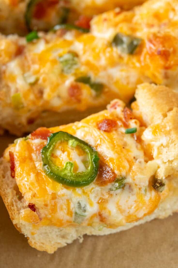 Close-up of a single piece of jalapeño popper cheese bread with melty cheese, bacon, and jalapeño on top.