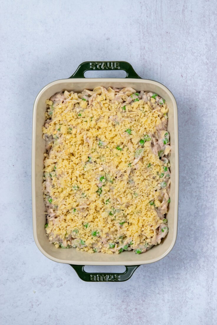 Assembled tuna noodle casserole in baking dish topped with buttery panko parmesan crumbs.
