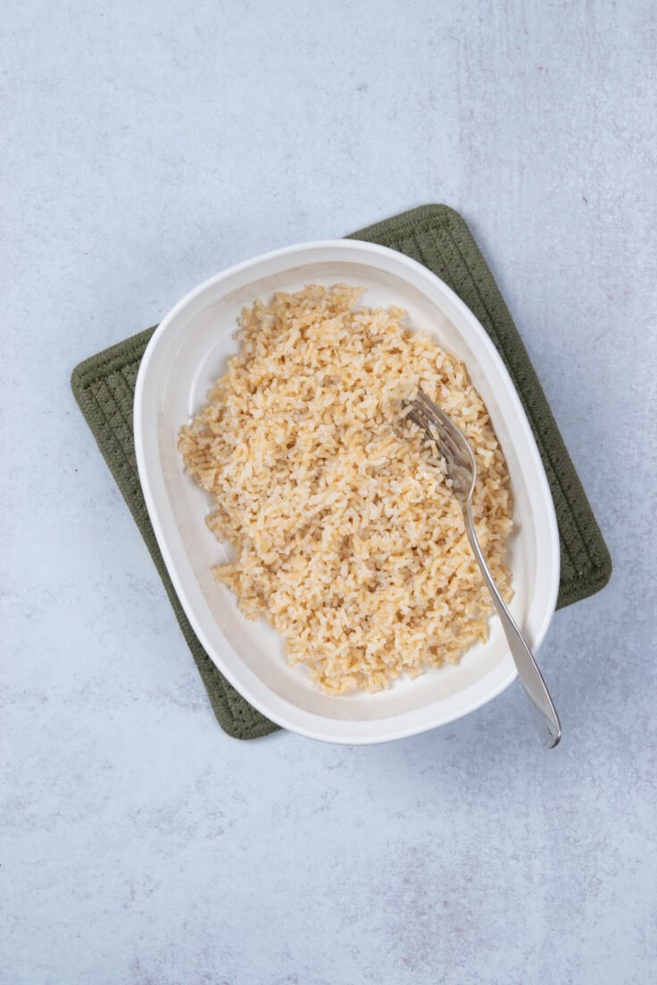 A casserole dish filled with cooked and fluffed brown rice.