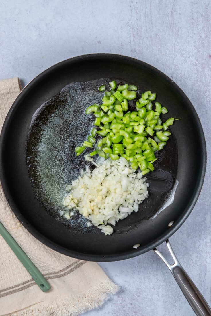 Sauteeing onion and celery in skillet for classic tuna casserole recipe.