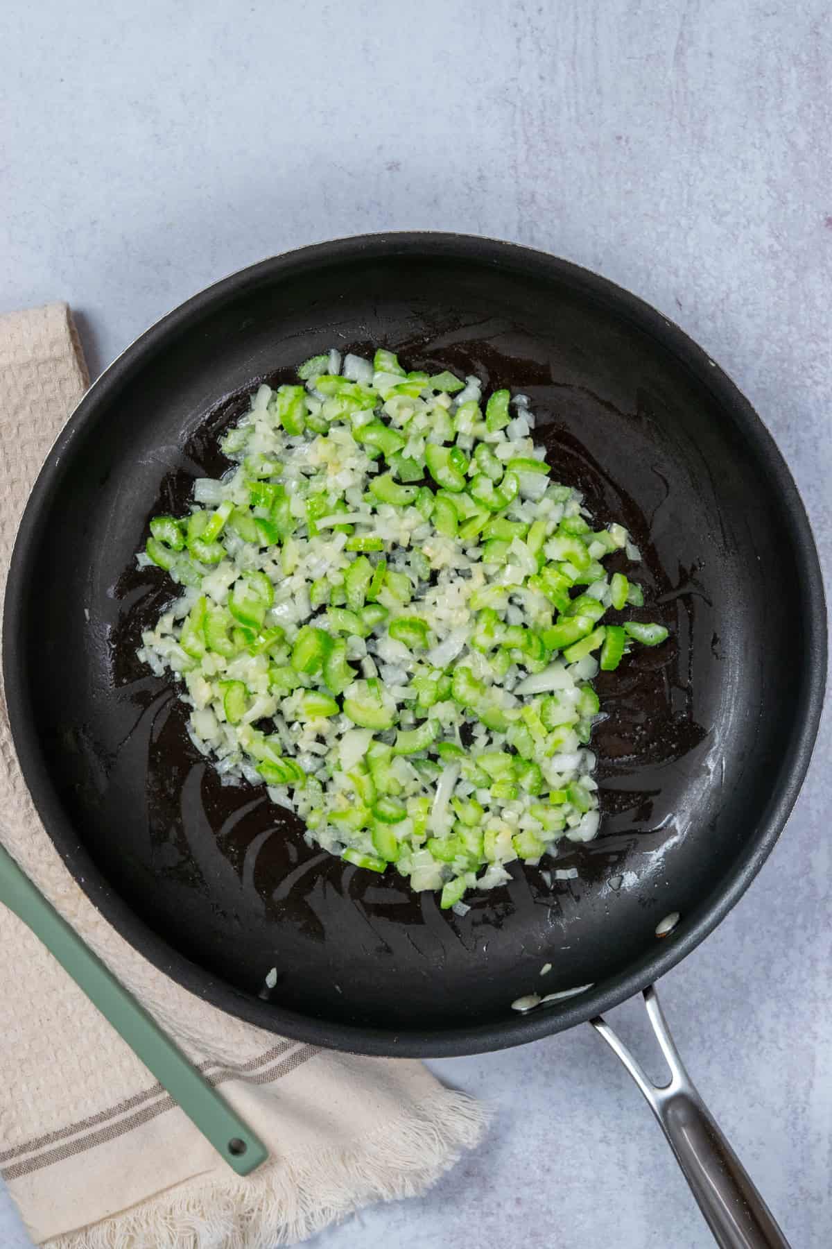 Sauteed onion and celery in skillet for classic tuna casserole recipe.