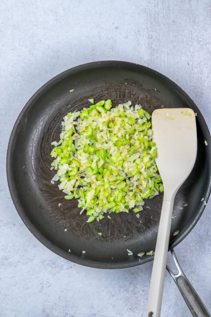 Sautéed diced onions and celery wilted in a pan.
