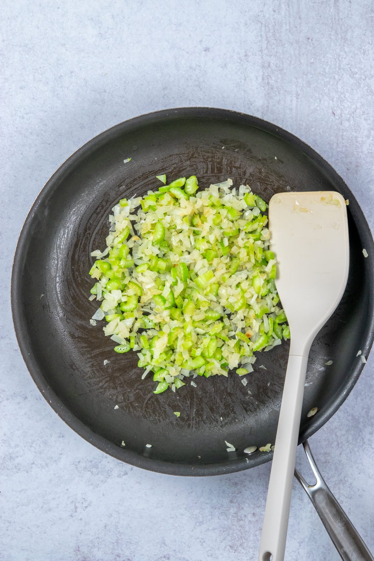 Sautéed diced onions and celery wilted in a pan.