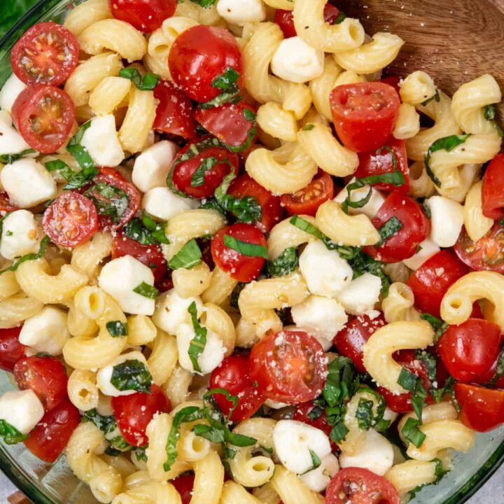 Overhead view of caprese pasta salad with cavatappi pasta, juicy grape tomatoes, pearl mozzarella, and fresh basil tossed in a light vinaigrette.