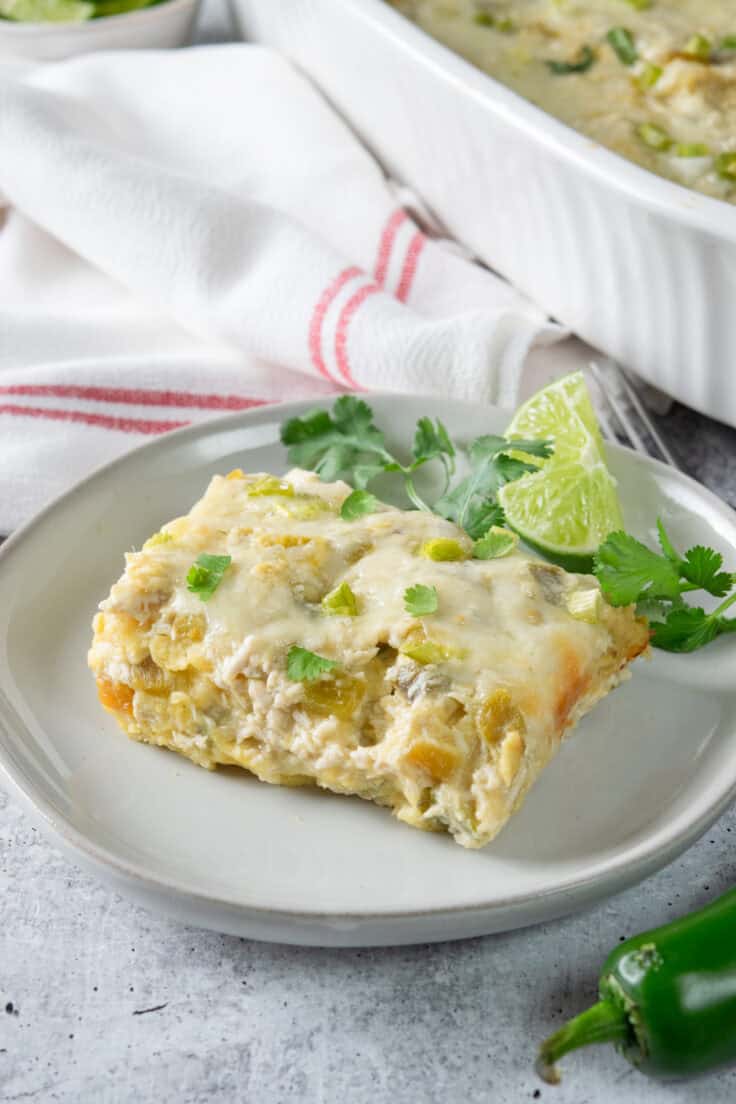 Slice of green chicken enchilada casserole with melted cheese and fresh chopped cilantro on top.