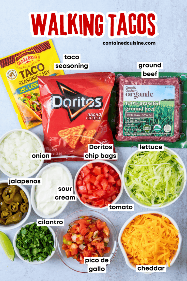 Overhead view of all the labeled ingredients for walking tacos, including seasoned taco meat, Doritos chips, and a variety of fresh toppings and mix-ins.