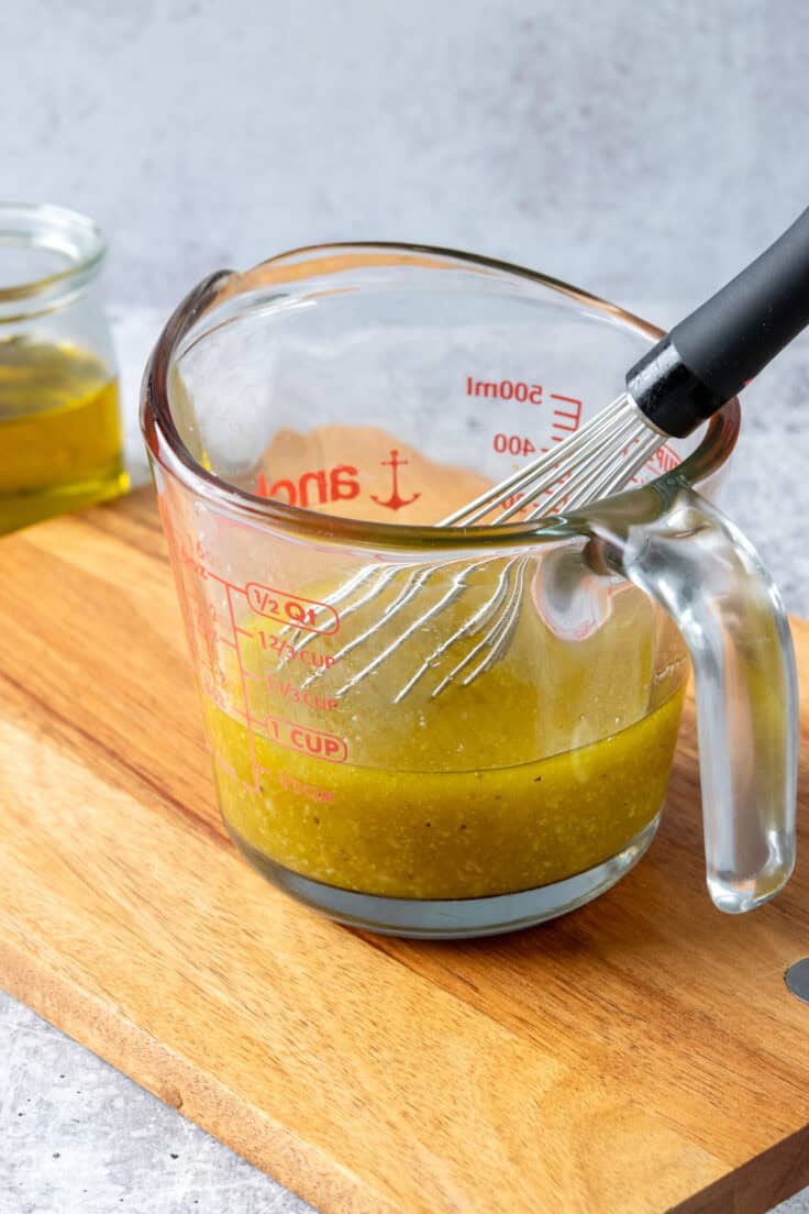 White balsamic vinaigrette being whisked together with olive oil and parmesan in a bowl.