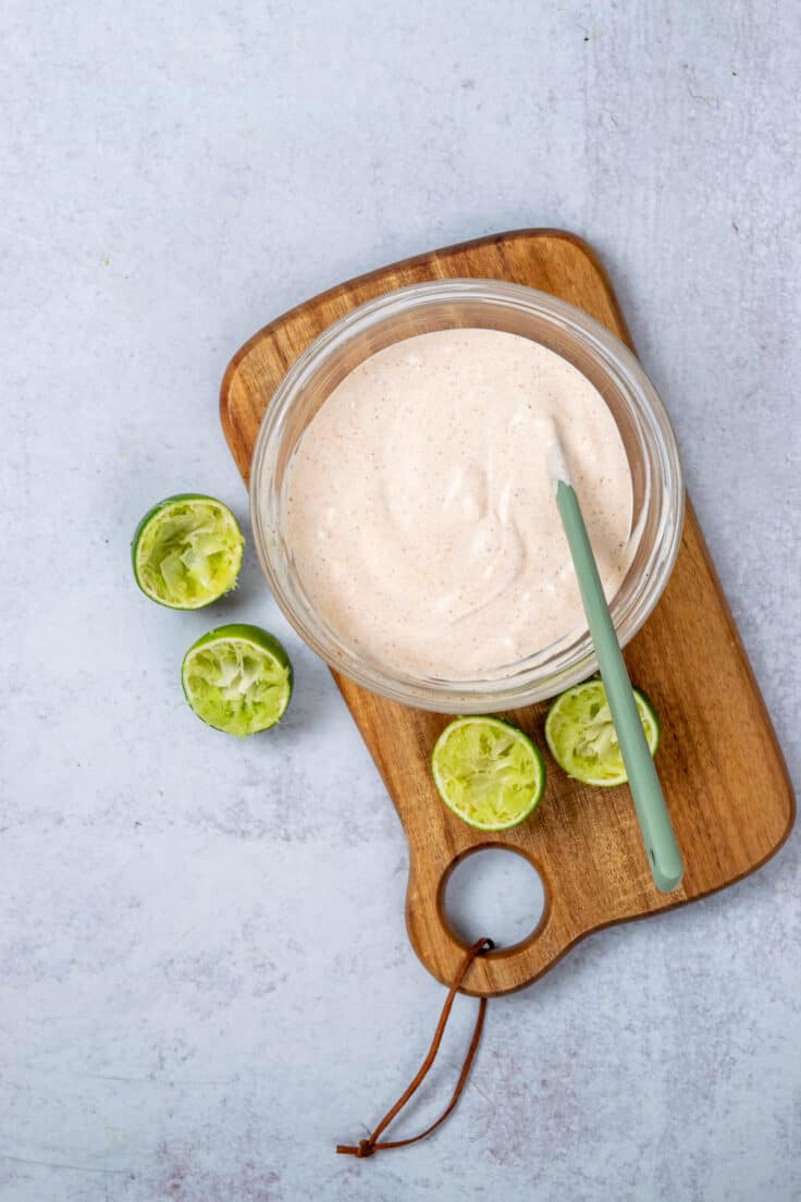 Creamy lime dressing being whisked together in a small glass bowl.