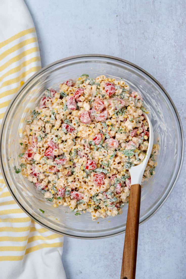 Mexican street corn pasta salad fully mixed with creamy dressing coating all ingredients.