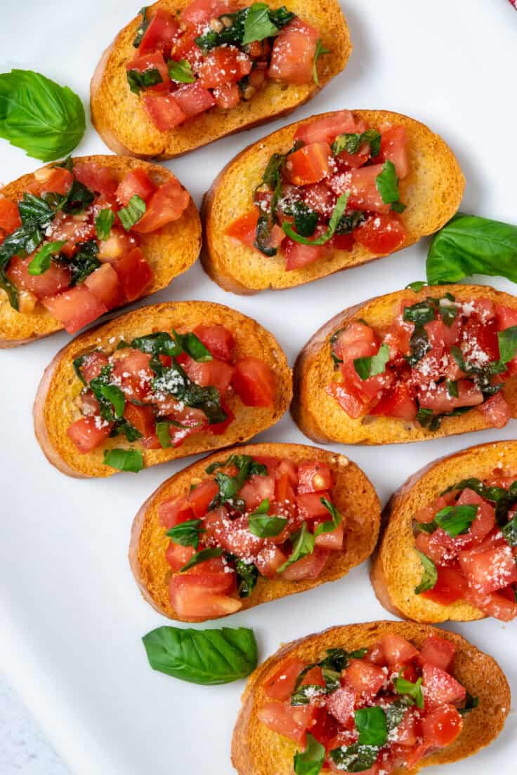 Platter of classic tomato bruschetta topped with parmesan and fresh basil.