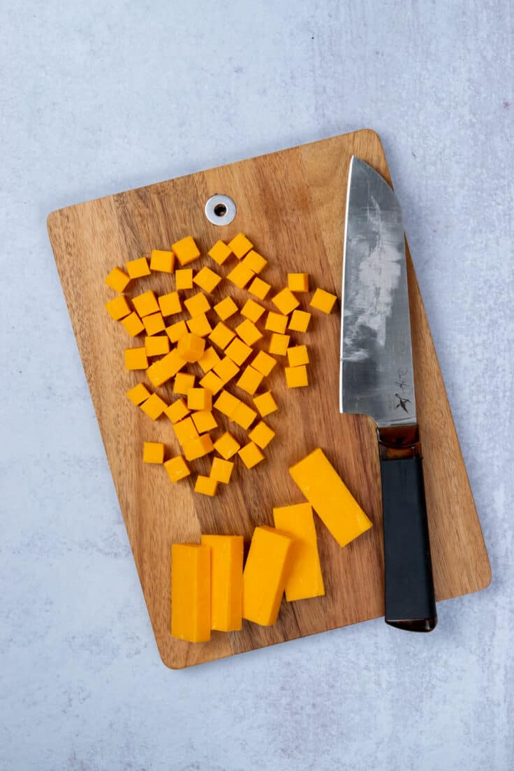 Cubes of sharp cheddar cheese on a cutting board before being chilled for homemade Cheez-Its.