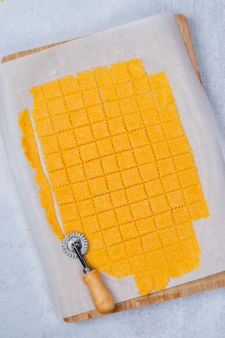 Homemade Cheez-Its dough cut into small square crackers before baking.