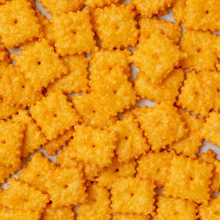 Overhead view of crispy homemade Cheez-Its baked until golden, with a hole in the center of each cracker and a sprinkle of flaky sea salt on top.