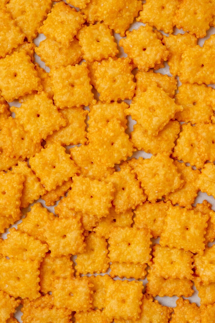 Overhead view of crispy homemade Cheez-Its baked until golden, with a hole in the center of each cracker and a sprinkle of flaky sea salt on top.