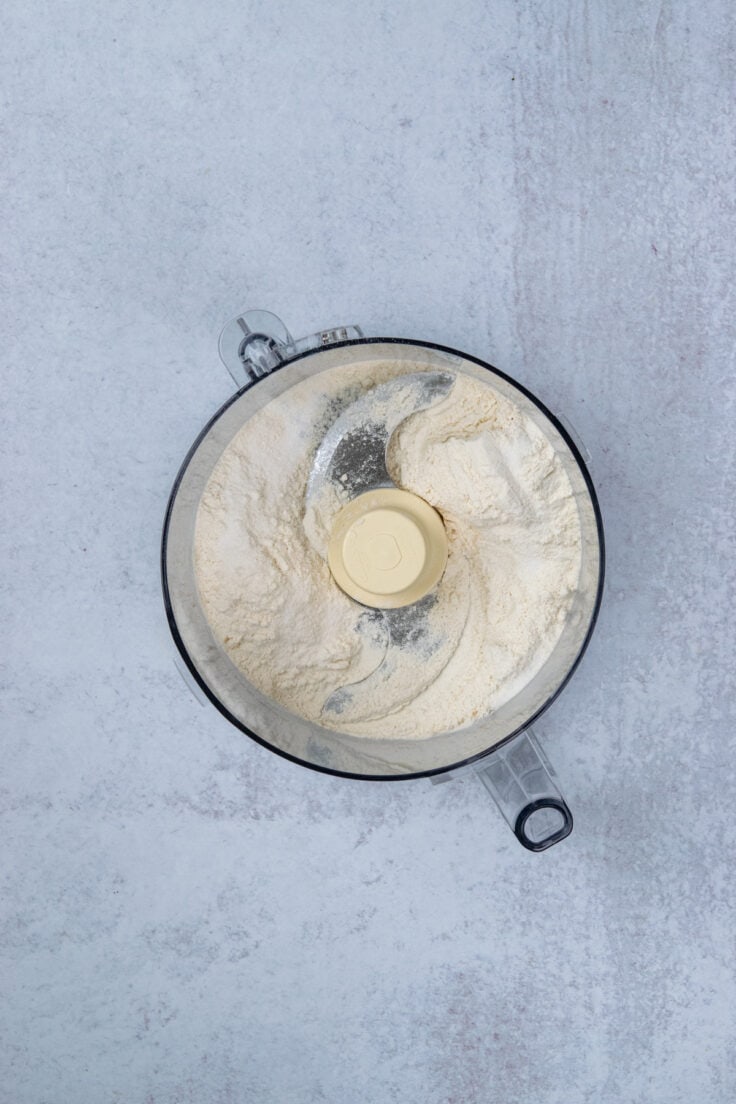 Flour and salt in a food processor bowl fitted with the S blade for making homemade Cheez-Its.