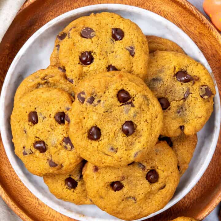 Homemade pumpkin chocolate chip cookies stacked on a plate ready to serve.