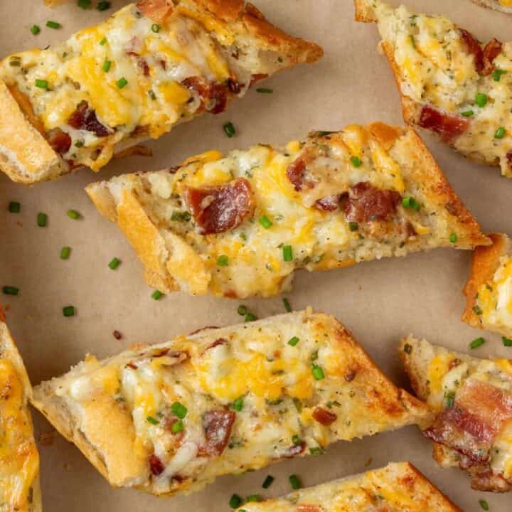 Overhead view of sliced bacon ranch cheese bread topped with melted cheese and pieces of bacon on a tray.