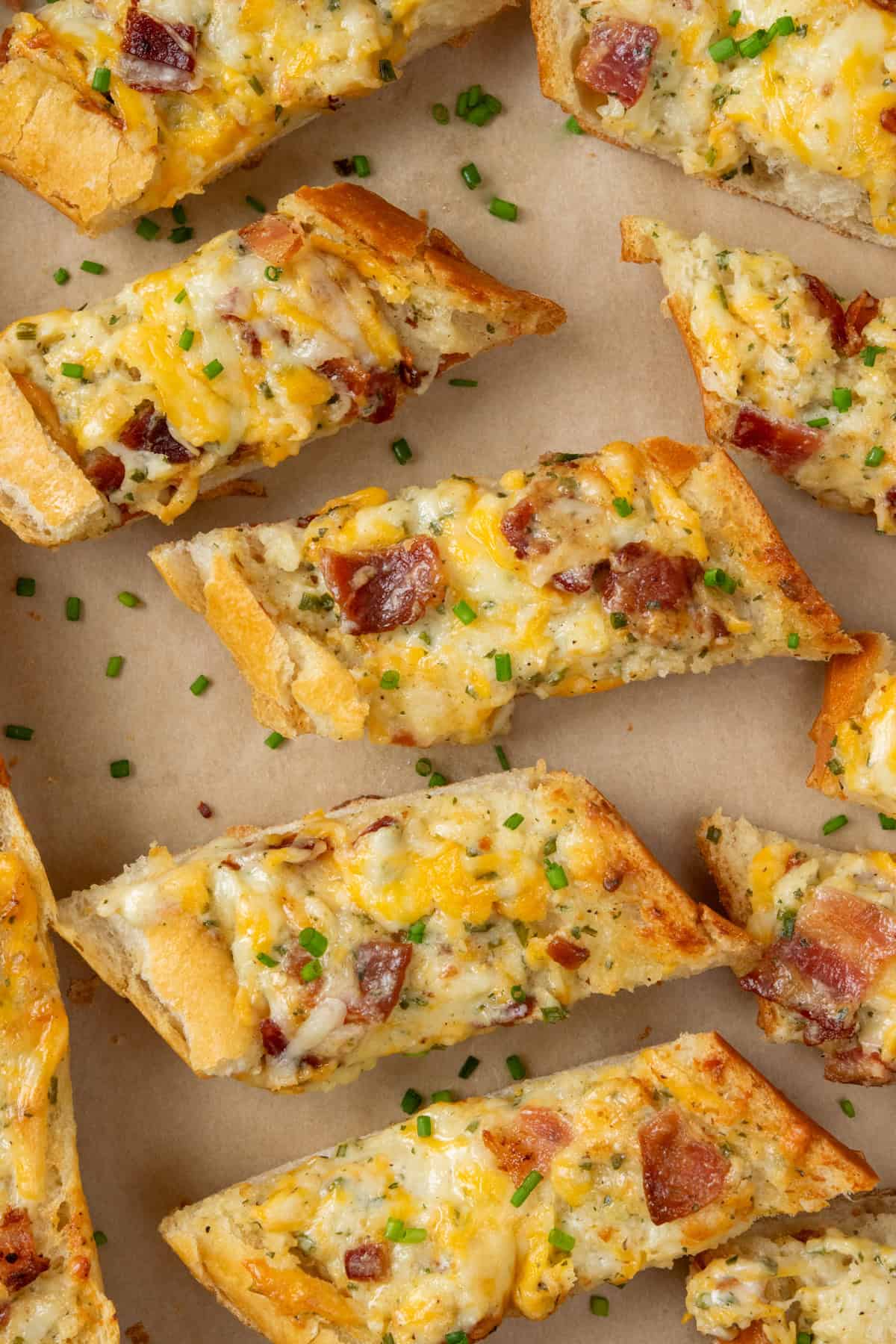 Overhead view of sliced bacon ranch cheese bread topped with melted cheese and pieces of bacon on a tray.
