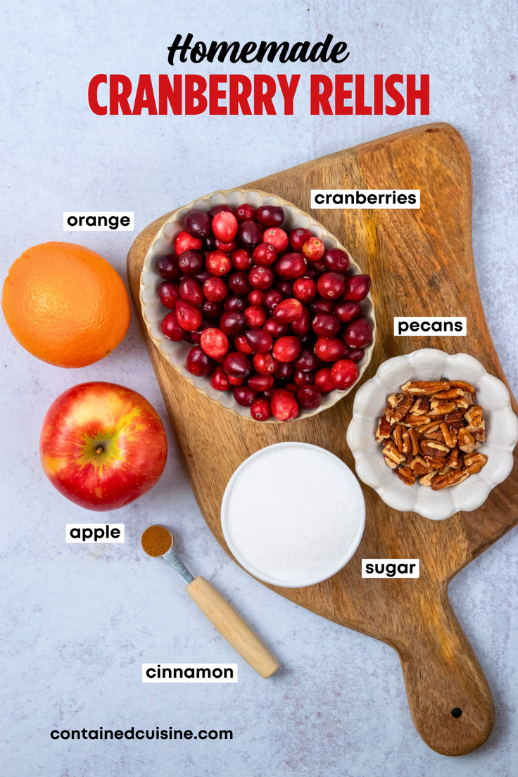 An overhead view of the labeled ingredients for homemade cranberry orange relish, including fresh cranberries, orange, apple, sugar, cinnamon, and pecans for this easy no-cook Thanksgiving recipe.